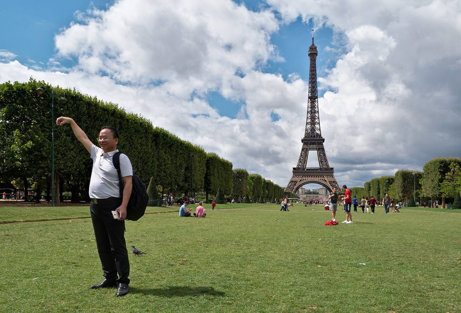 Turist som poserer for et bilde foran Eiffeltårnet på Champ de Mars