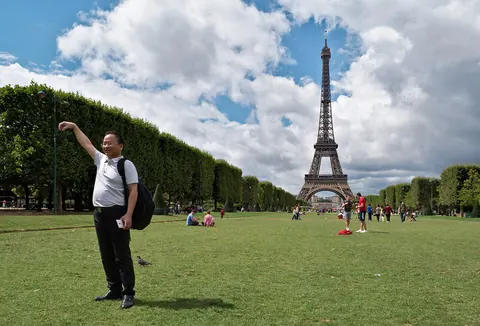 Turist som poserer for et bilde foran Eiffeltårnet på Champ de Mars
