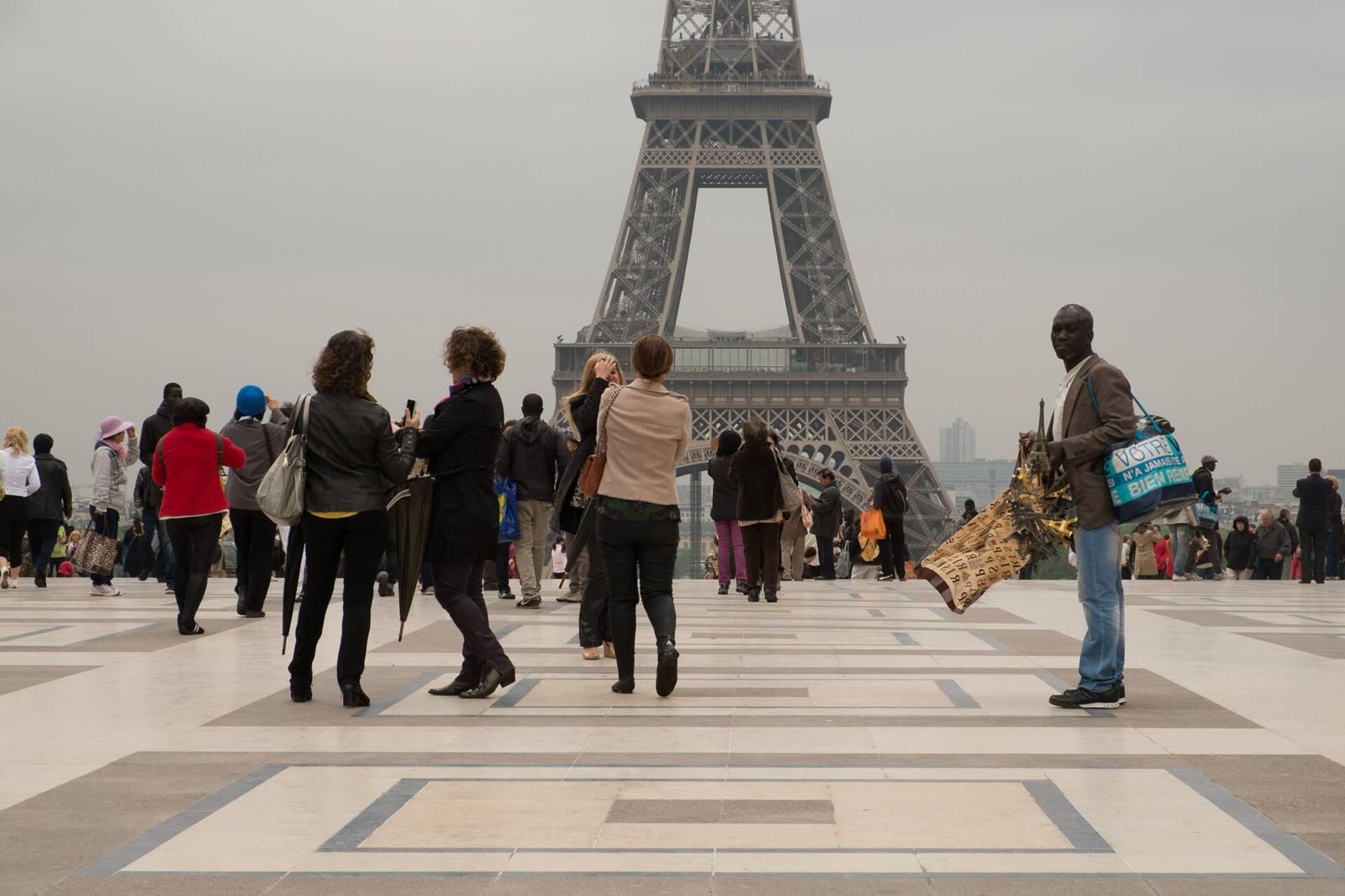 Gateselgere og turister på Trocadéro med Eiffeltårnet bak