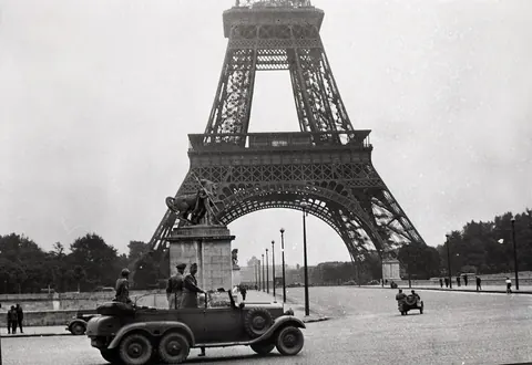 Eiffeltårnet med en bil foran, historisk fotografi